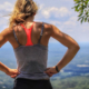 Frau stet auf Hügel und überblickt Landschaft. optimumtraining.at